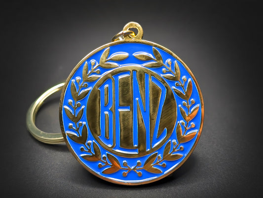 Round gold metal Benz double-sided keychain with a blue background and the classic "BENZ" logo surrounded by laurel wreaths.