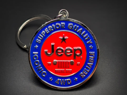 Round blue and red metal Jeep double-sided keychain with a classic grille logo and "SUPERIOR QUALITY ICONIC RELIABLE" text.