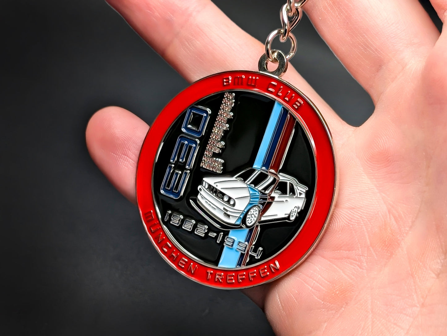 Close-up of a circular metal badge keychain featuring a detailed BMW E30 M3 illustration and the M motorsport logo.