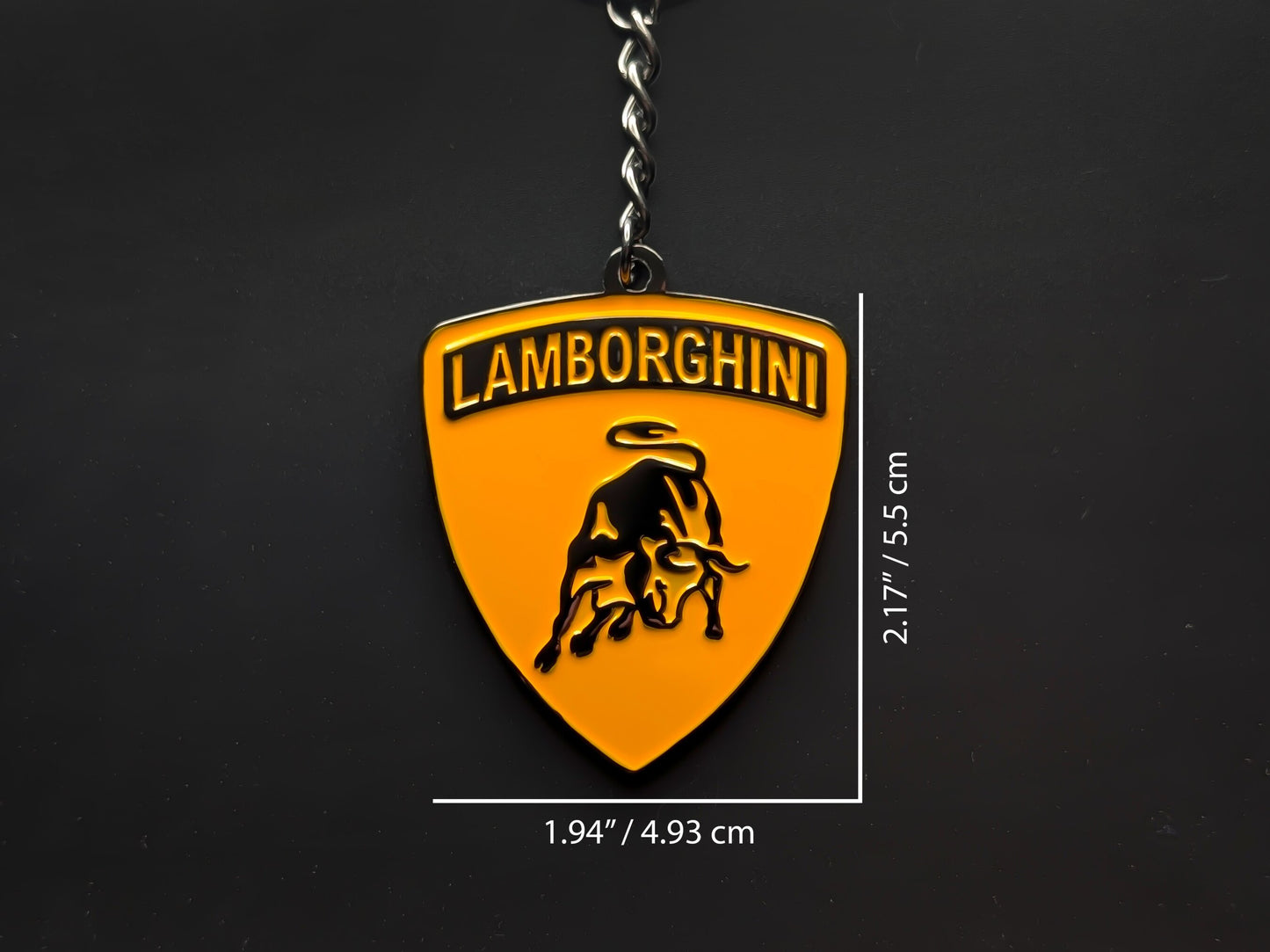 Dimension shot of the Lamborghini orange badge keychain showing a size of 2.17 inches by 1.94 inches (5.5 cm by 4.93 cm).
