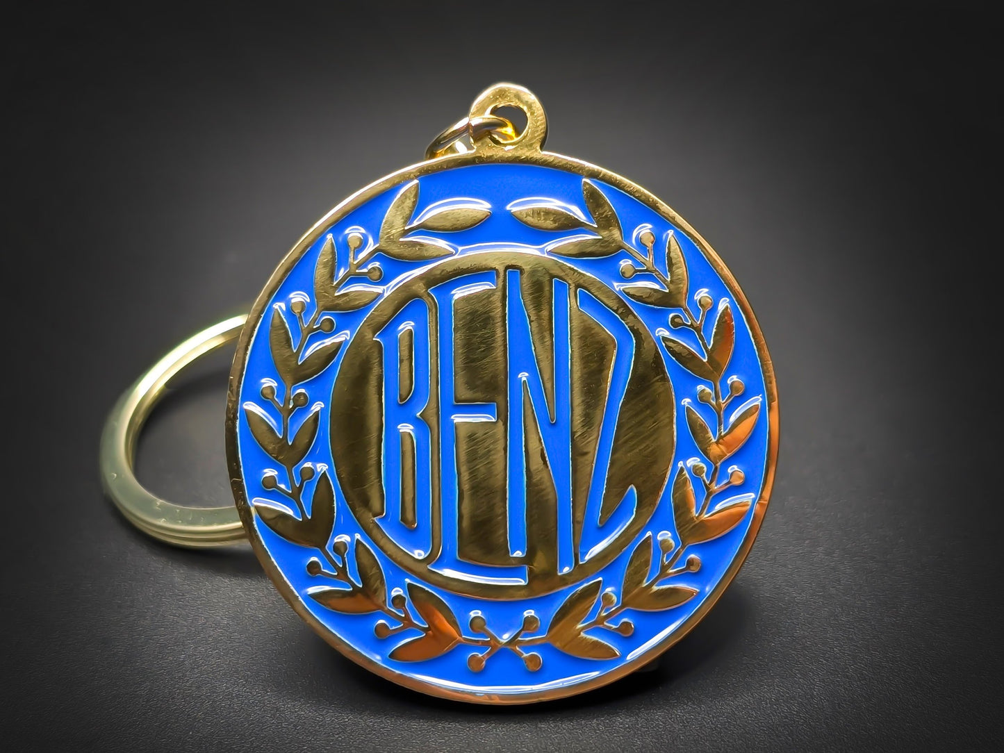 Round gold metal Benz double-sided keychain with a blue background and the classic "BENZ" logo surrounded by laurel wreaths.