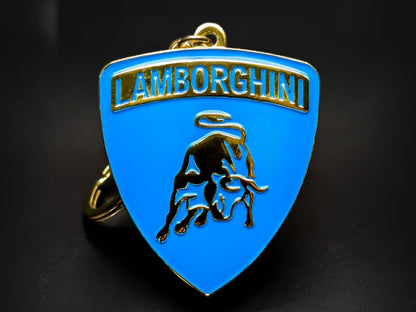 Shield-shaped blue and gold Lamborghini metal keychain with a golden bull logo and the "Lamborghini" wordmark.