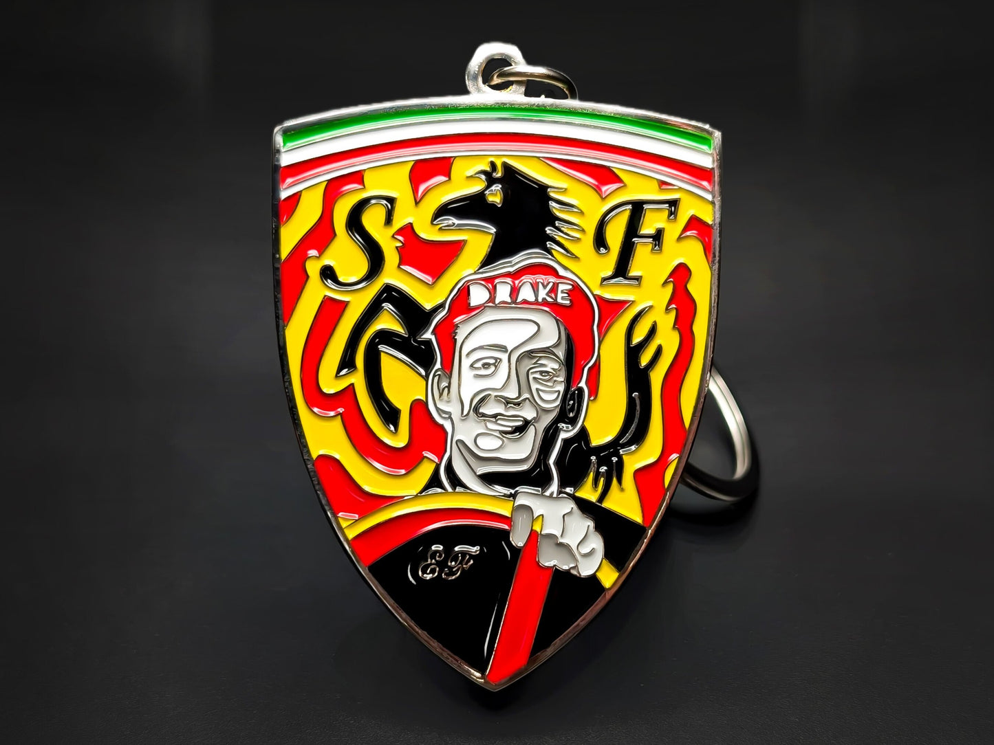 Red, white, and yellow Ferrari shield metal keychain with a drawing of a smiling Enzo Ferrari and a black horse emblem.