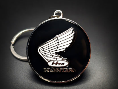 Round black and silver Honda keychain with a white winged logo and "HONDA" text.