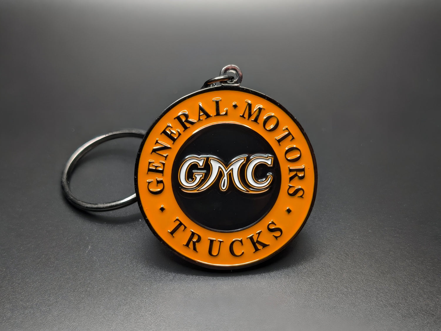 GMC vintage keychain displaying the iconic GMC Trucks orange emblem. Front view.