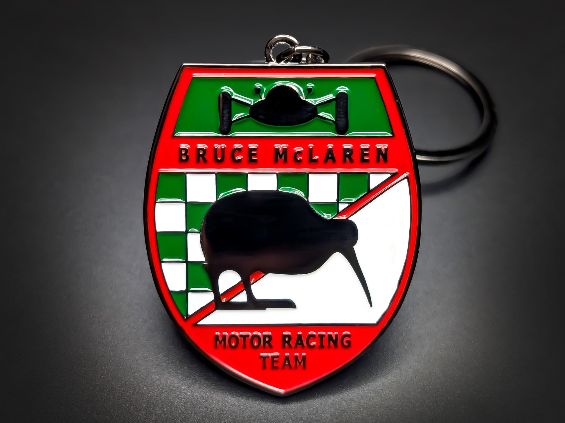 Red, green, and white McLaren racing team shield metal keychain with a kiwi bird logo and "BRUCE MCLAREN" text.