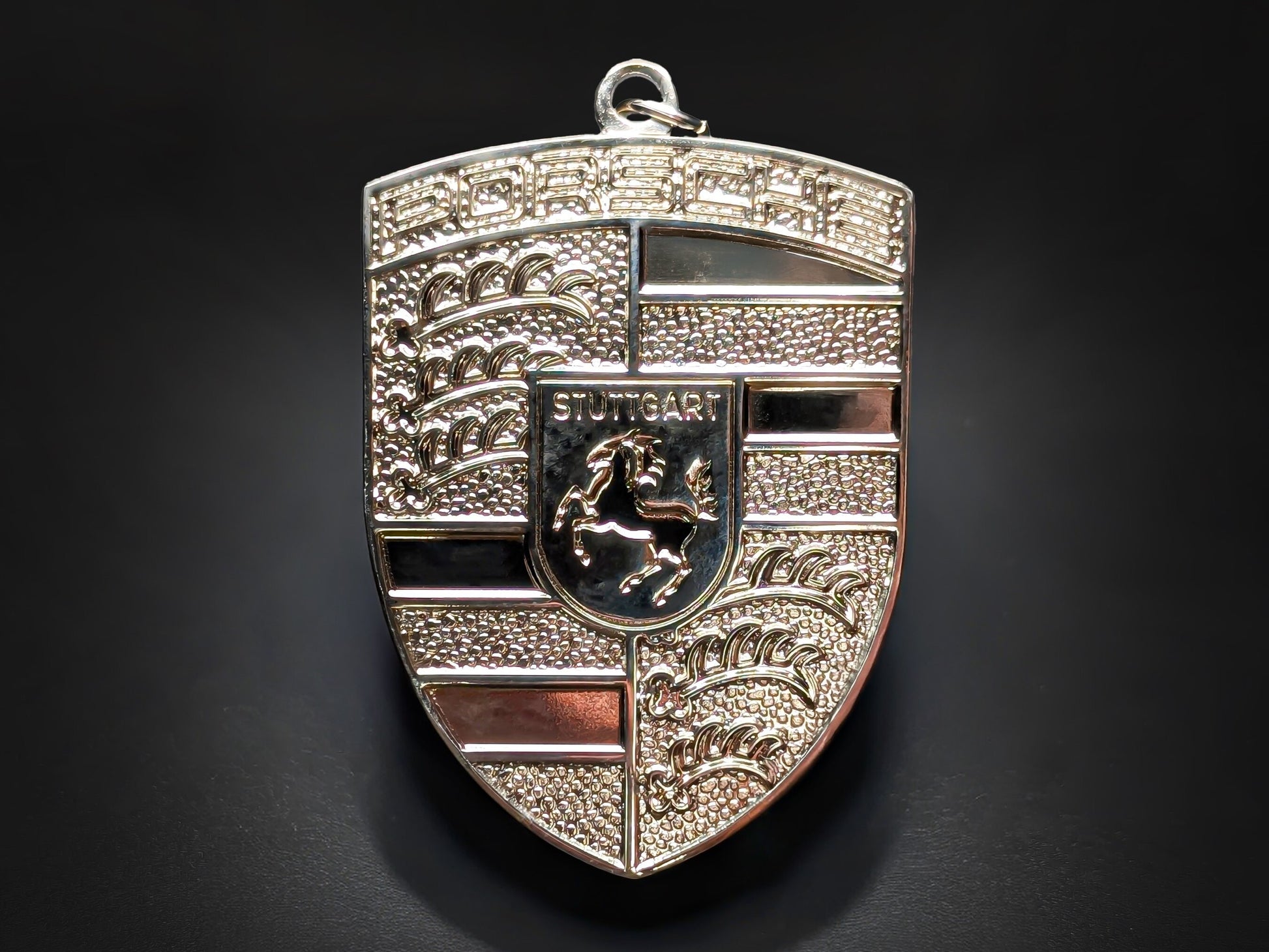 Textured silver Porsche shield metal keychain with "PORSCHE" and "STUTTGART" text, featuring a horse emblem.