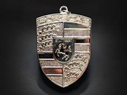 Textured silver Porsche shield metal keychain with "PORSCHE" and "STUTTGART" text, featuring a horse emblem.