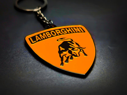 Shield-shaped orange and black Lamborghini metal keychain with a black bull logo and the "Lamborghini" wordmark.