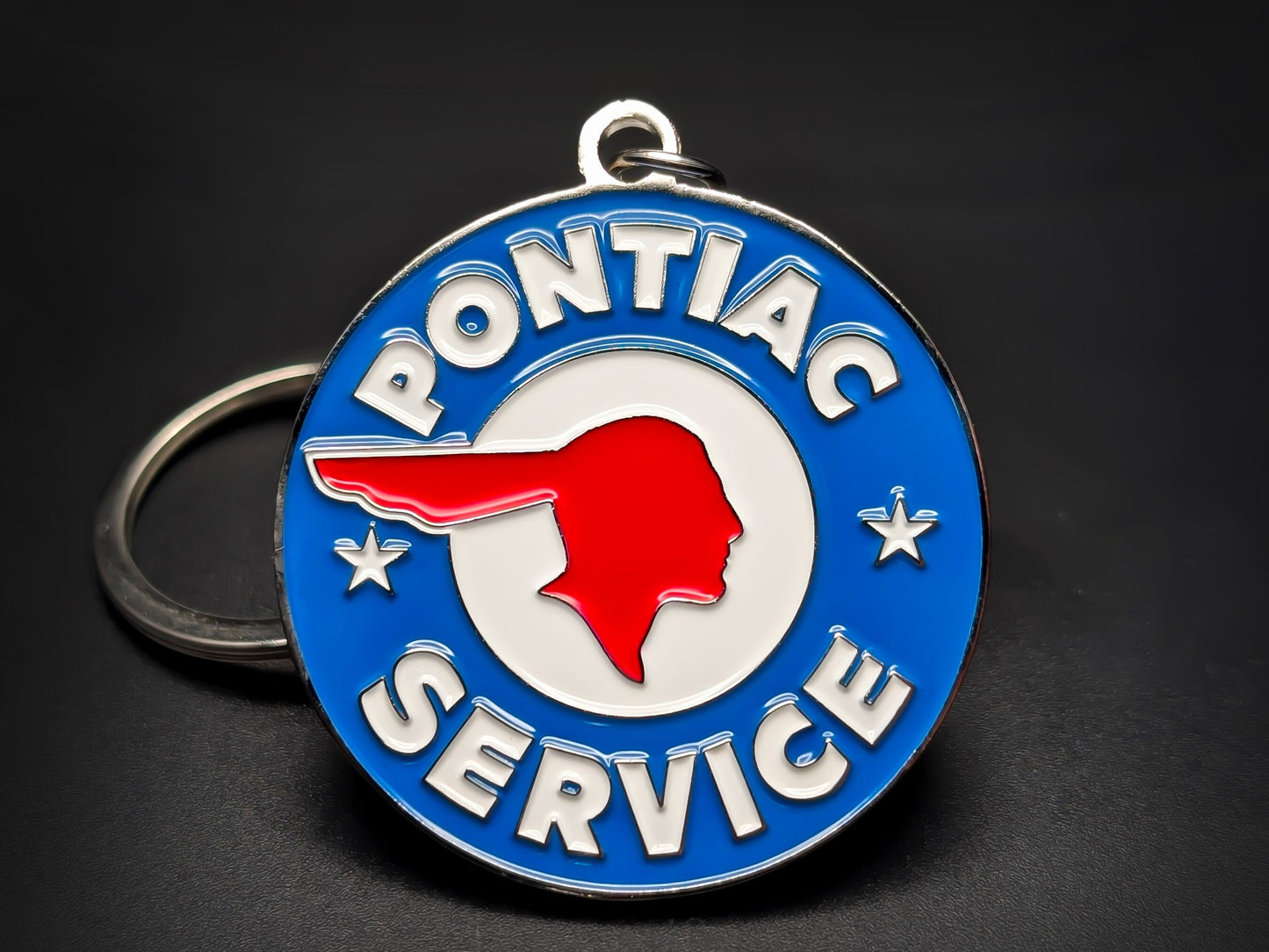 Round blue and white Pontiac Service double-sided metal keychain with a red Native American head profile and stars.