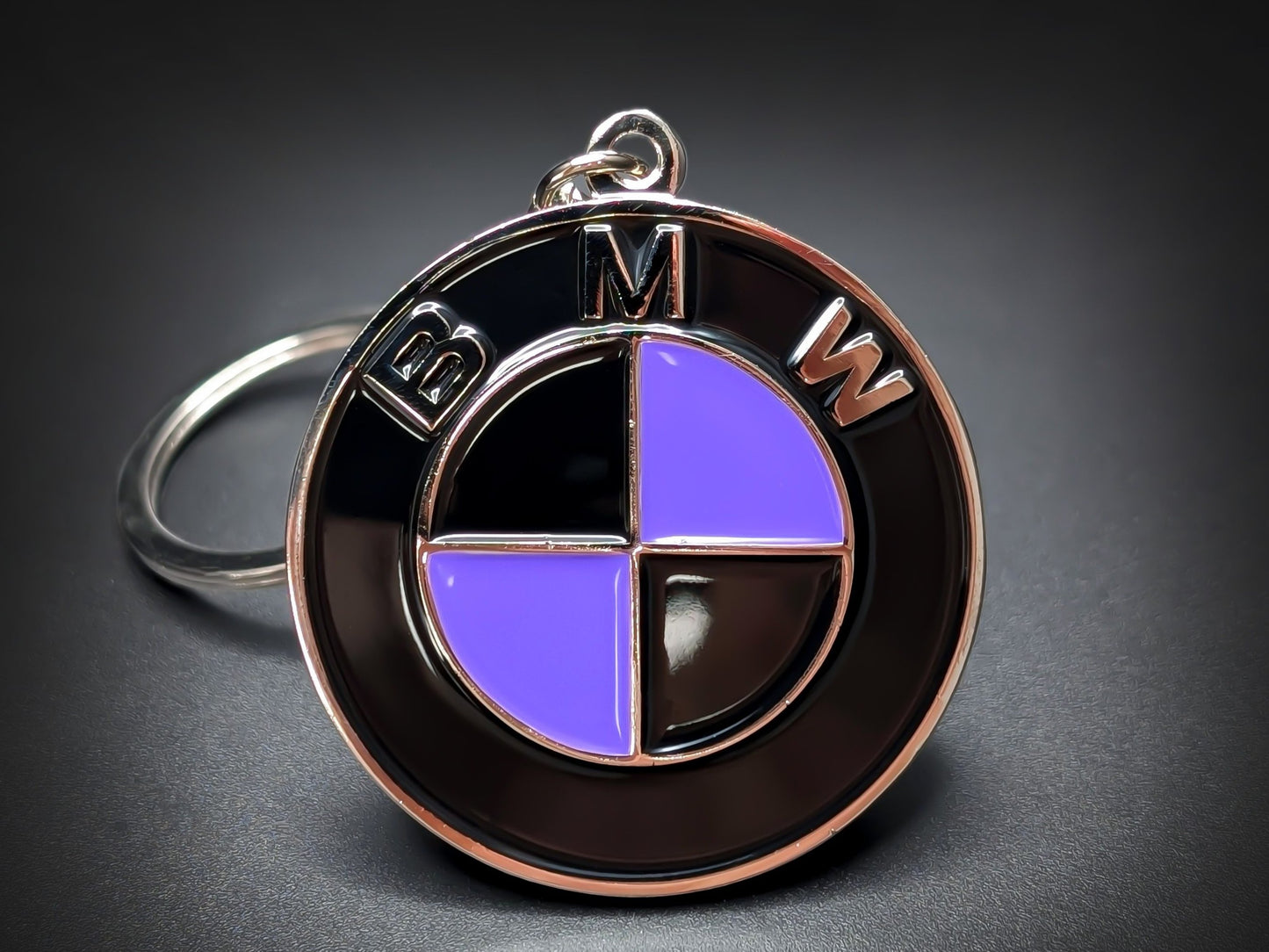 Round black and silver BMW double-sided metal keychain with a purple and black checkered logo and "BMW" text.