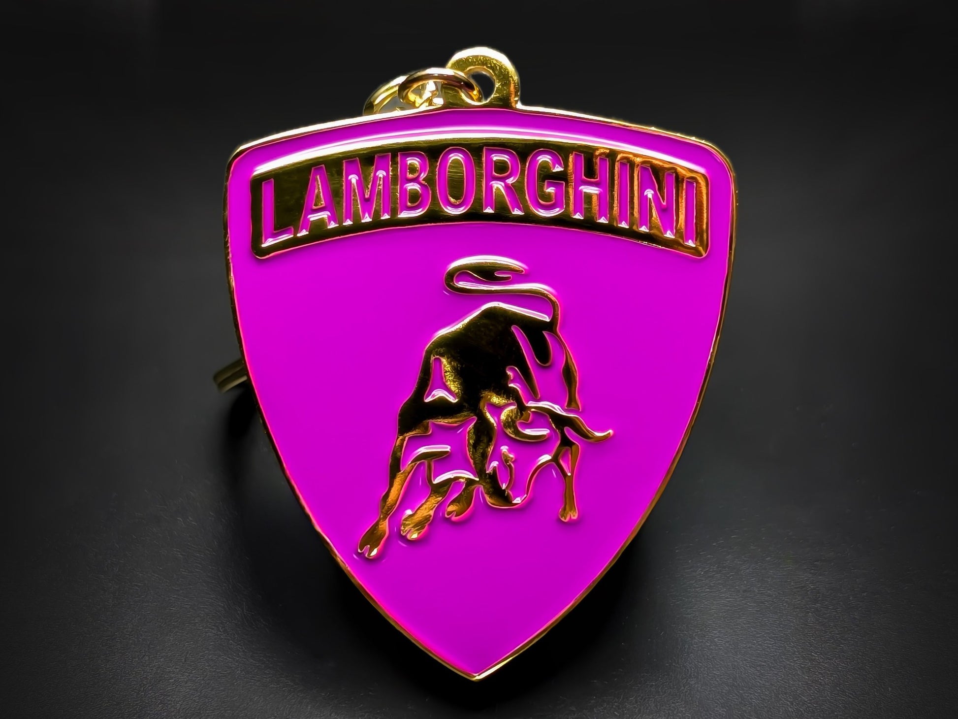 Shield-shaped purple and gold Lamborghini metal keychain with a golden bull logo and the "Lamborghini" wordmark.