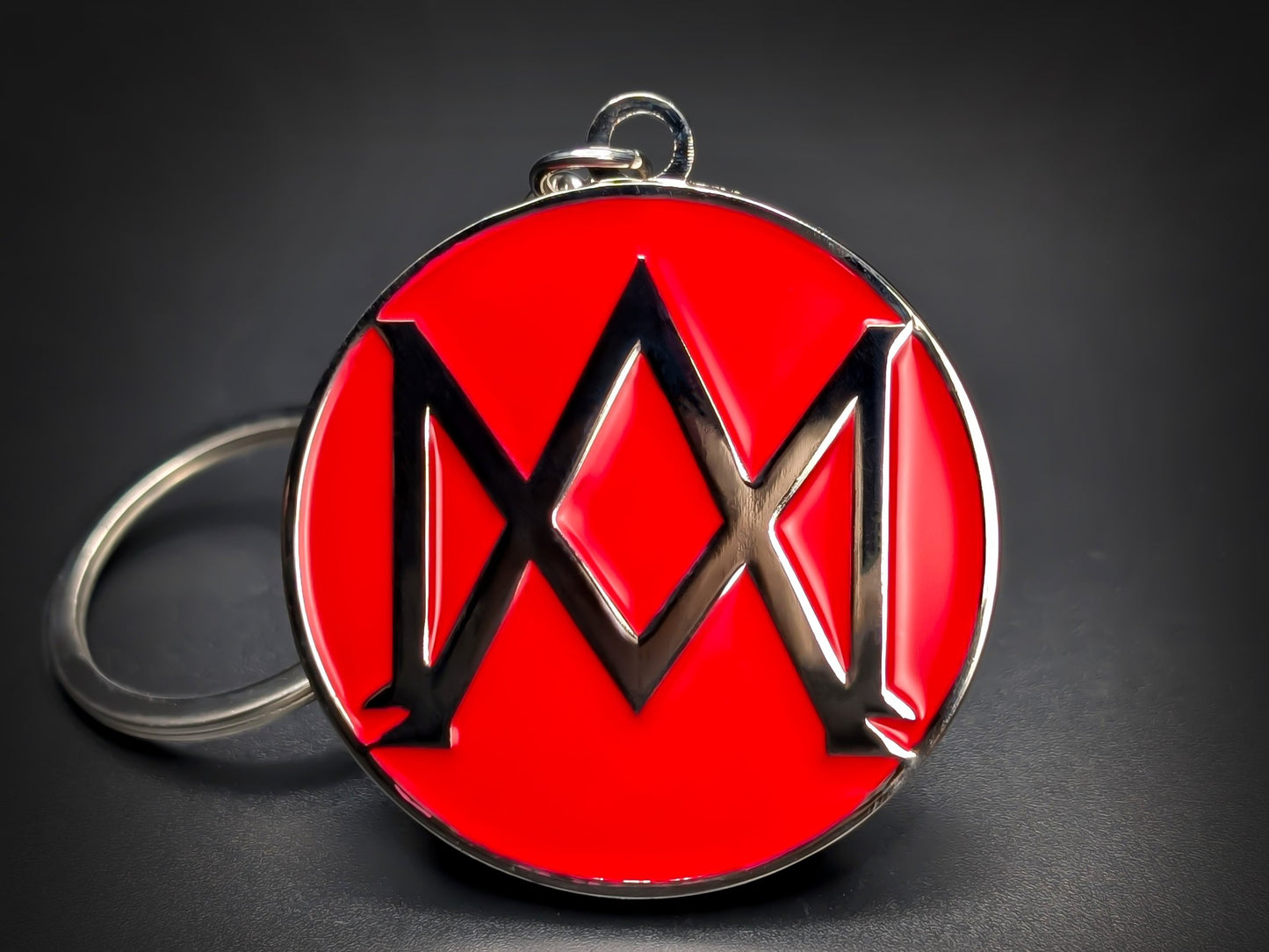 Round red and silver Aston Martin keychain with a large "M" shaped logo in the center.