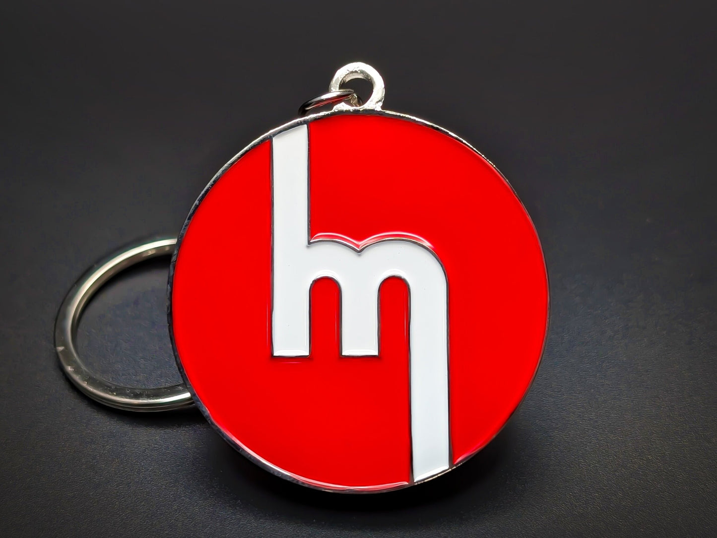Round red double-sided metal Mazda keychain with a stylized white "M" logo.