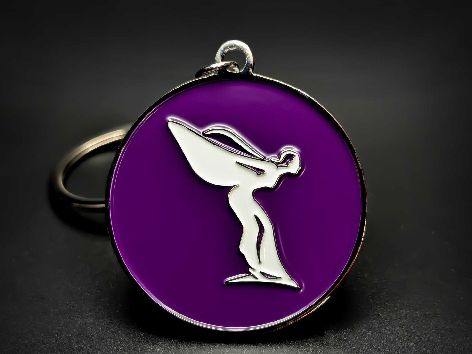 Round purple and silver Rolls-Royce keychain with a white "Spirit of Ecstasy" flying lady logo.