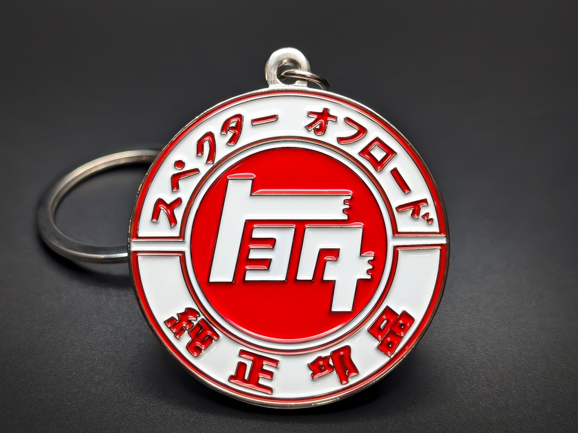 Round white and red Toyota metal keychain featuring the classic "TOYOTA" script within a circle, surrounded by Japanese characters.