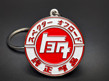 Round white and red Toyota metal keychain featuring the classic "TOYOTA" script within a circle, surrounded by Japanese characters.