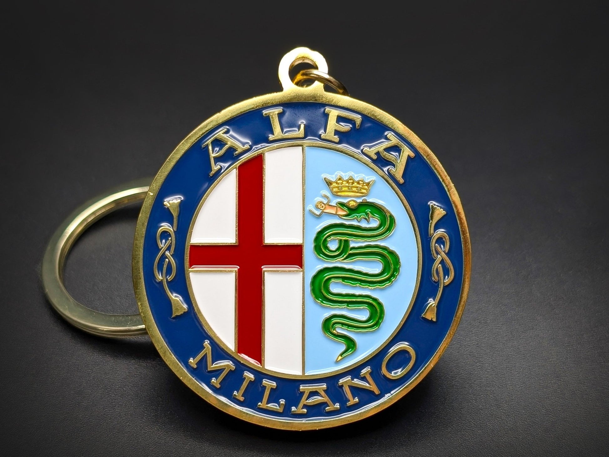 Vintage Alfa Romeo Milano badge keychain with gold-plated lettering, red cross, and green biscione snake on a blue enamel border.