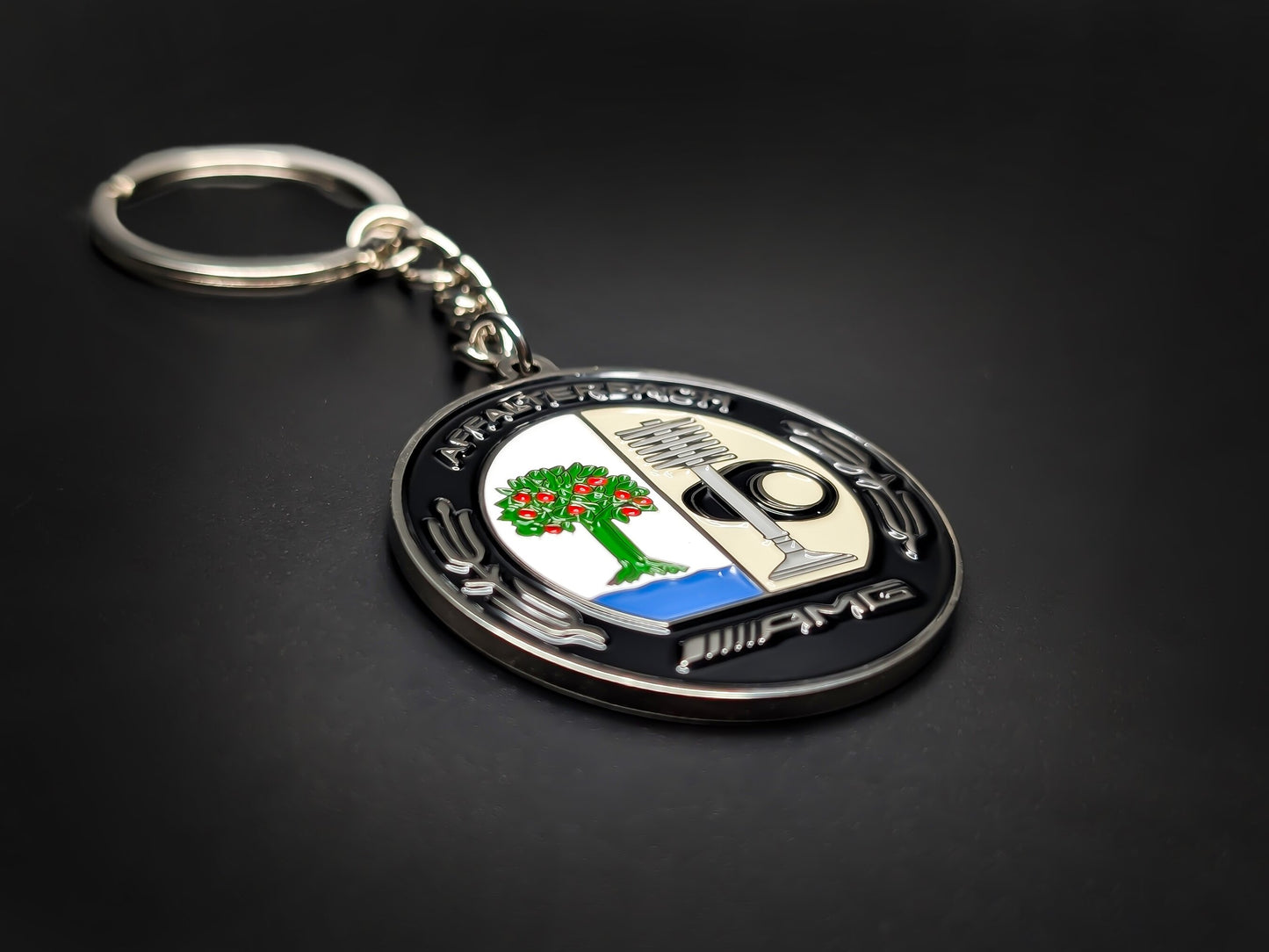 High-quality AMG performance heritage keychain on a dark background, showcasing the polished silver-tone rim and durable linked chain.