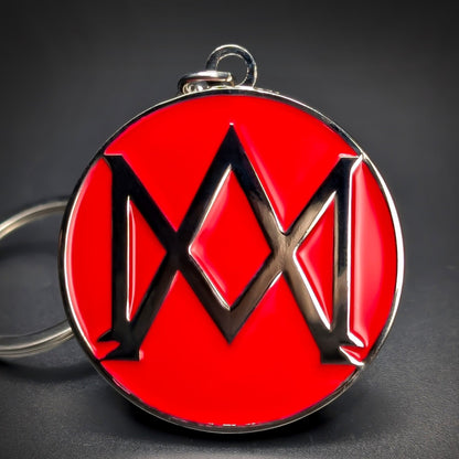 Double-sided metal Aston Martin badge keychain with a black abstract wing emblem on a glossy red enamel background, chrome rim and loop at the top, on a dark gradient surface.