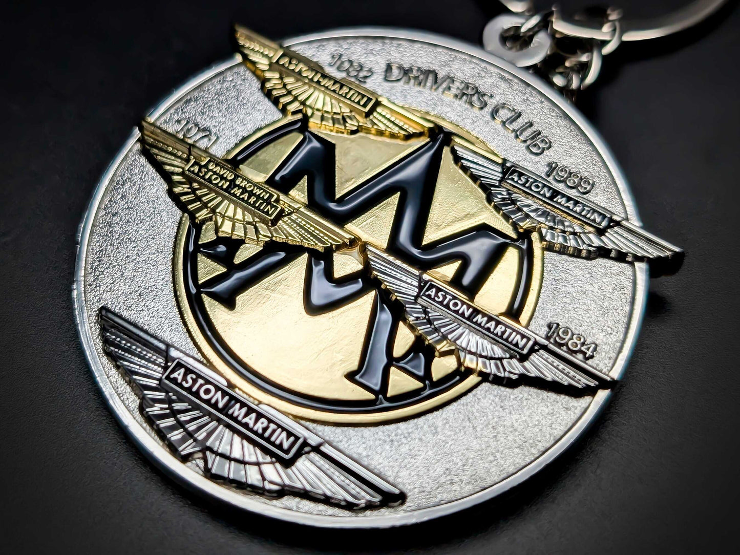 High-detail Aston Martin Drivers Club badge keychain featuring multi-layered wings and heritage years in gold and silver.