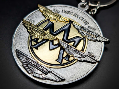 High-detail Aston Martin Drivers Club badge keychain featuring multi-layered wings and heritage years in gold and silver.