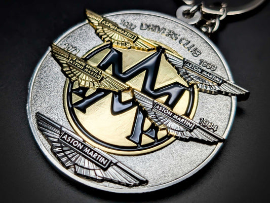 High-detail Aston Martin Drivers Club badge keychain featuring multi-layered wings and heritage years in gold and silver.