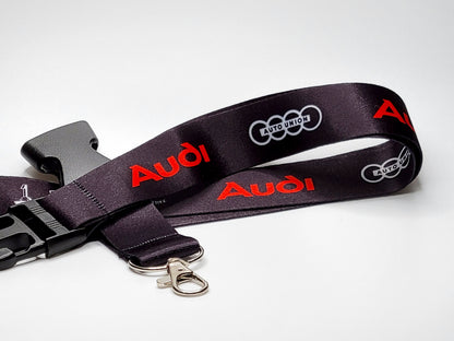 Black Audi lanyard featuring red embossed lettering, white Auto Union logo, and a durable silver lobster claw clasp.