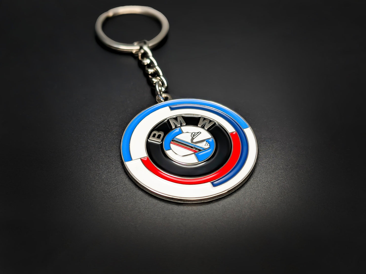 High-gloss BMW M 50 Years anniversary badge keychain on a dark background, showing the premium metal chain and ring.