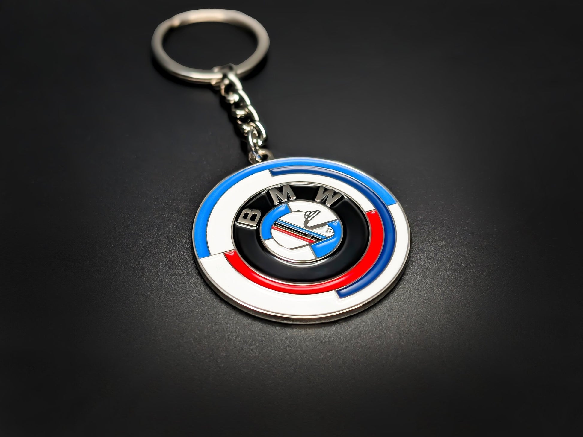 High-gloss BMW M 50 Years anniversary badge keychain on a dark background, showing the premium metal chain and ring.