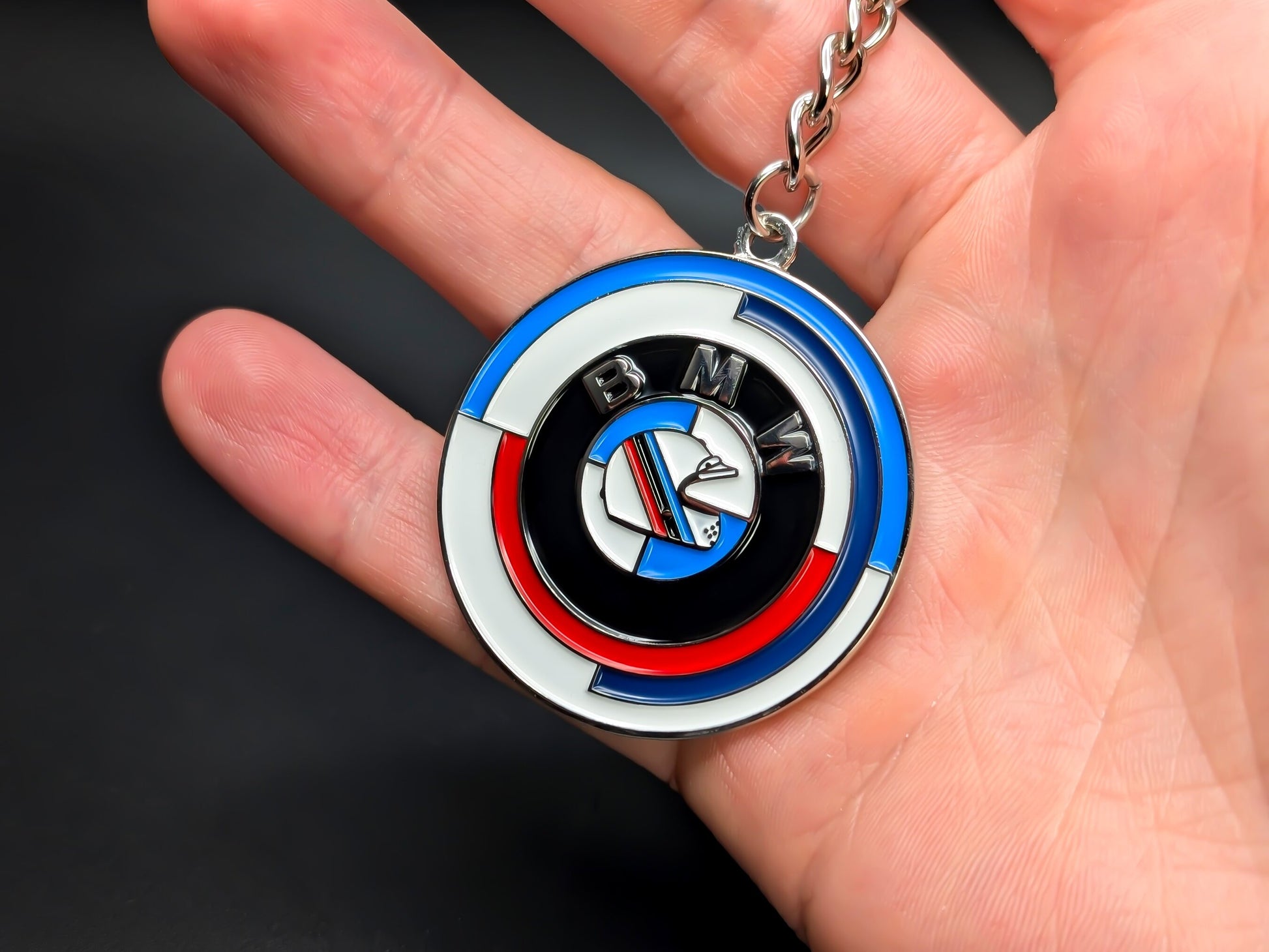 BMW anniversary heritage badge keychain held in hand, displaying the 50 Years of M logo and polished chrome lettering.