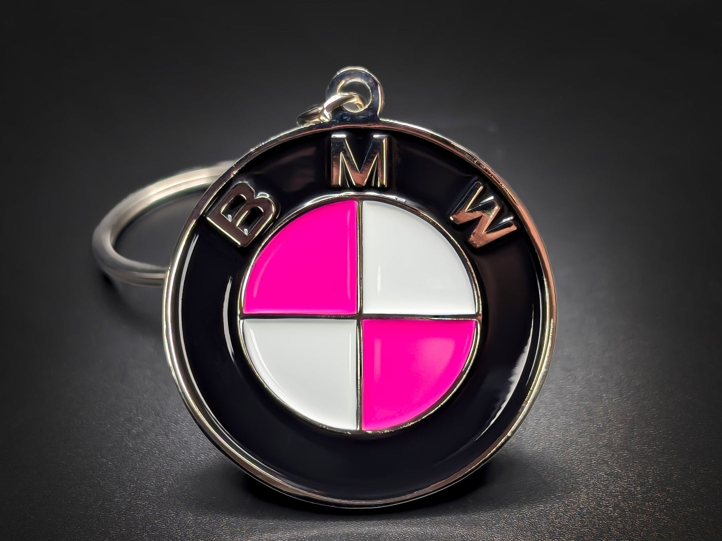 BMW roundel badge keychain featuring hot pink and white quadrants with polished silver-tone "BMW" lettering on a black outer ring.