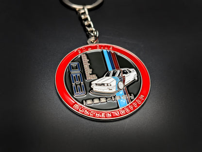 A hand holding the BMW E30 M3 badge keychain, showing the vibrant blue enamel and polished silver-tone metal.