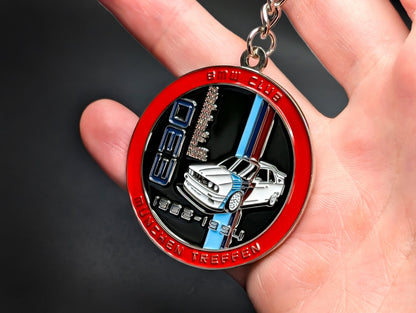 Close-up of a circular metal badge keychain featuring a detailed BMW E30 M3 illustration and the M motorsport logo.