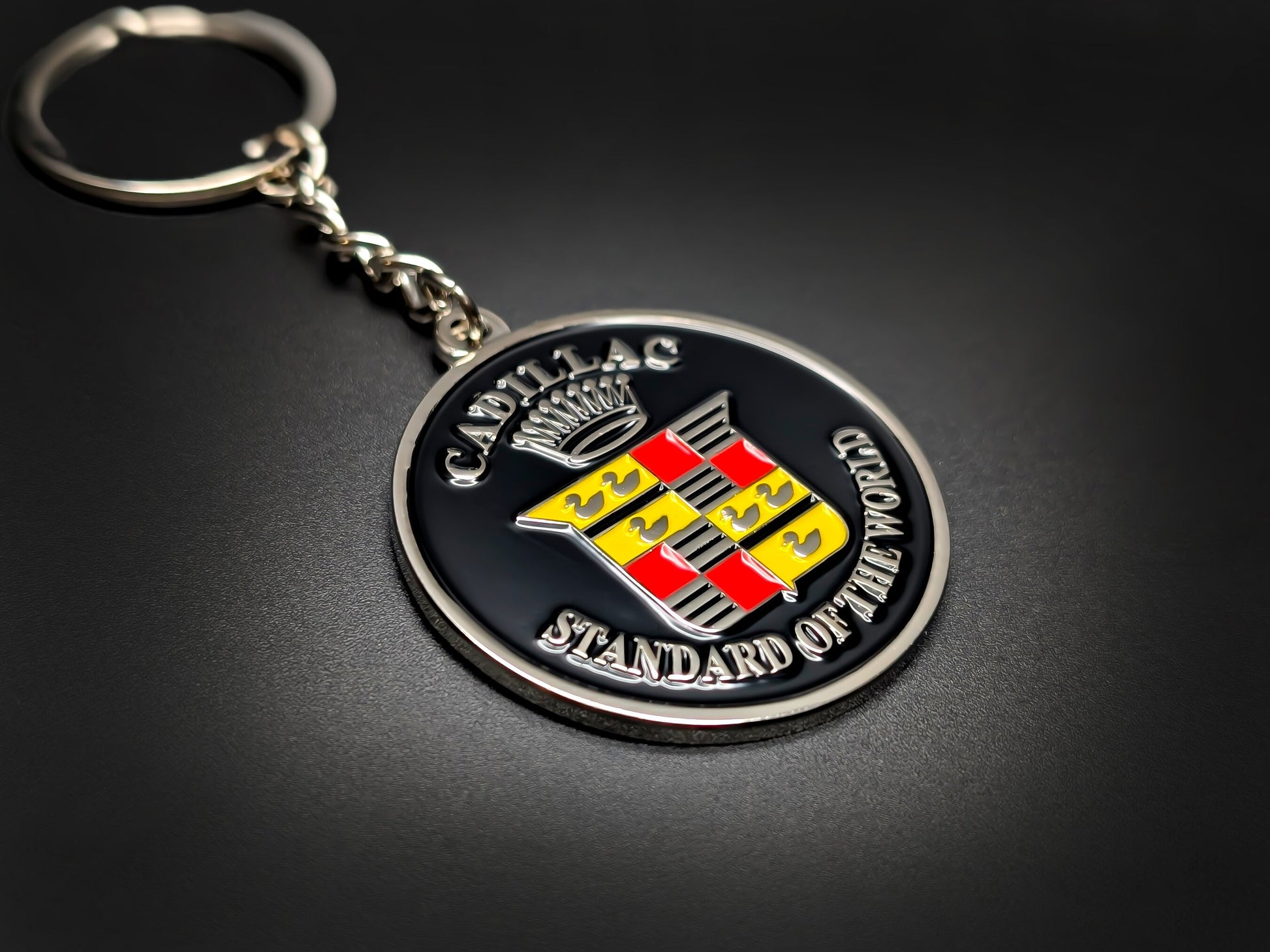 High-quality Cadillac crest keychain on a dark background, showcasing the polished silver-tone crown and durable metallic chain.