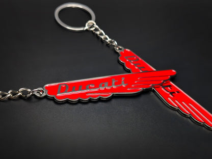 Close-up of two red Ducati vintage enamel keychains showcasing the vibrant color and 3D raised silver lettering.