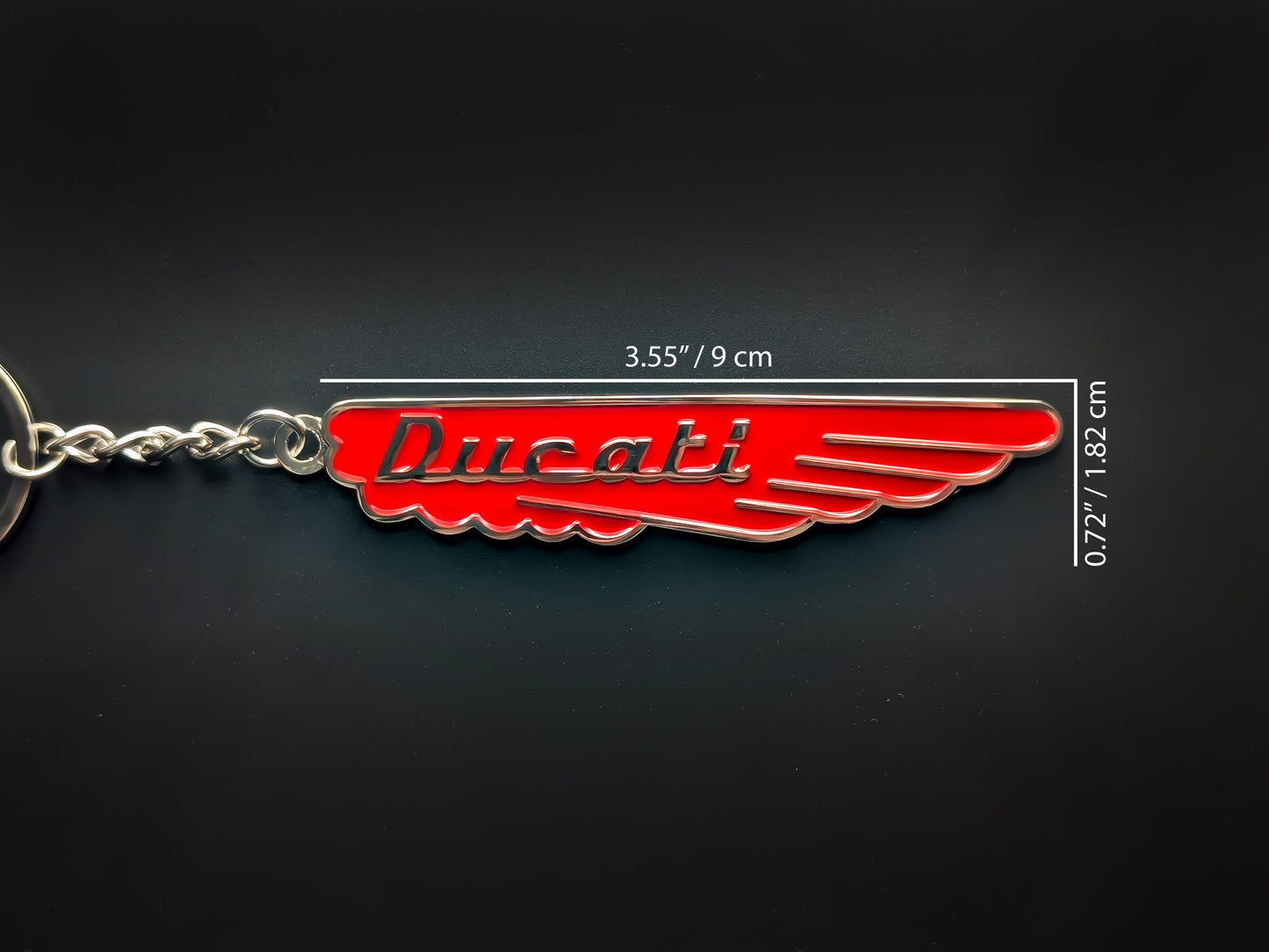 Hand holding the classic red Ducati enamel keychain highlighting the vibrant gloss finish and sturdy linked chain.