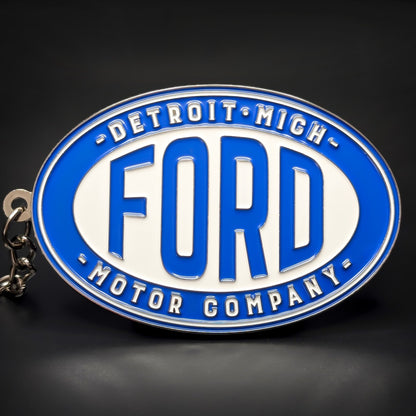 Double-sided metal Ford badge keychain, blue and white oval enamel medallion reading “Detroit Mich” above “Ford” and “Motor Company” below, chrome trim, linked chain to a silver split ring.