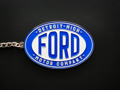 Overhead view of a Ford Detroit Motor Company keychain with a sturdy silver linked chain against a dark backdrop.