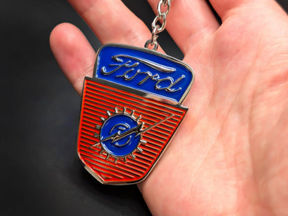 Hand holding a shield-shaped Ford vintage truck enamel badge keychain to demonstrate the premium metallic weight and vibrant 3D details.