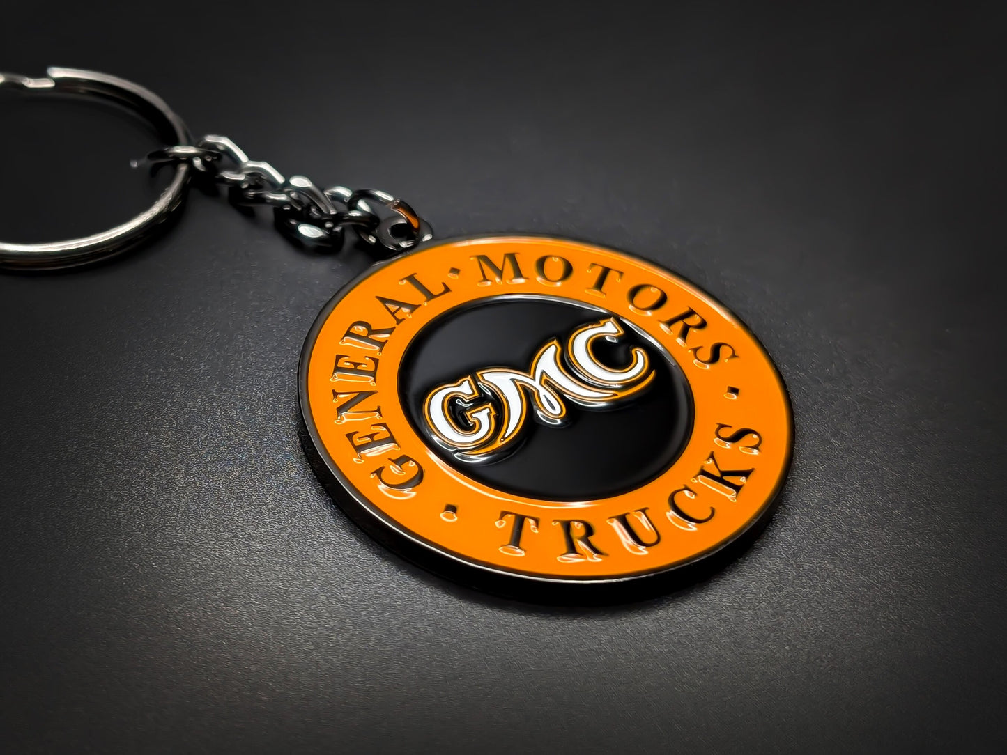 High-quality retro GMC heritage keychain on a dark background, showcasing the glossy enamel finish and durable gunmetal-finish chain.