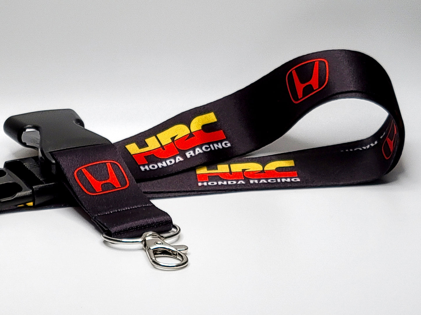 Black Honda Racing lanyard featuring the red HRC logo and yellow "Honda Racing" text, complete with a silver lobster claw clasp.