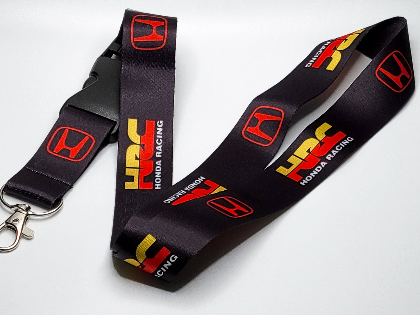 Premium black satin lanyard showcasing a repeating pattern of the red Honda "H" logo and the HRC racing wordmark.