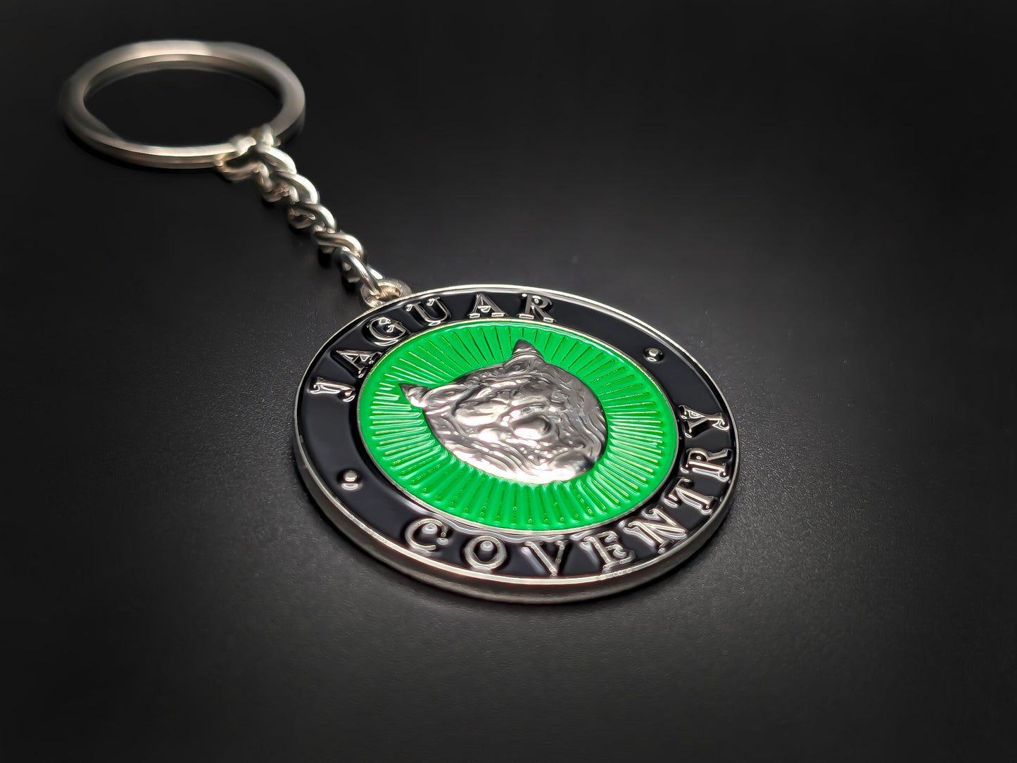 High-gloss Jaguar Coventry heritage badge keychain on a dark surface, showing the polished metallic rim and silver-tone chain.