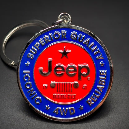 Double-sided metal Jeep badge keychain with a red center circle, black ‘Jeep’ script over a seven-bar grille icon, ringed in blue: ‘SUPERIOR QUALITY ICONIC RELIABLE 4WD,’ split ring, dark background.
