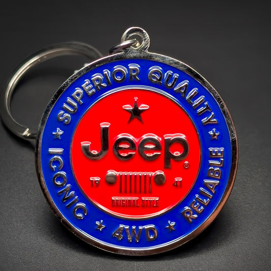 Double-sided metal Jeep badge keychain with a red center circle, black ‘Jeep’ script over a seven-bar grille icon, ringed in blue: ‘SUPERIOR QUALITY ICONIC RELIABLE 4WD,’ split ring, dark background.
