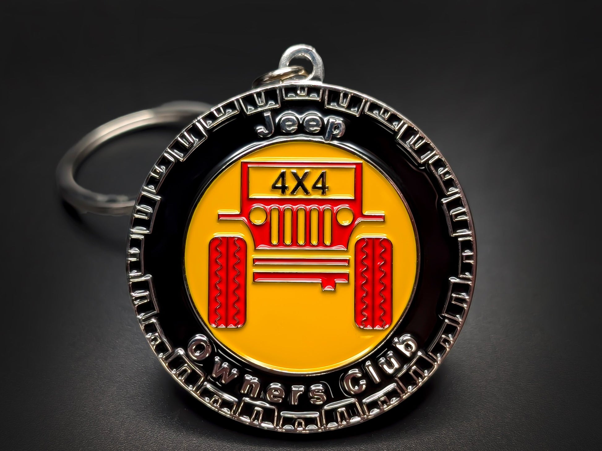 Close-up of a circular metal badge keychain featuring the classic seven-slot Jeep grille and "Jeep Club" branding.