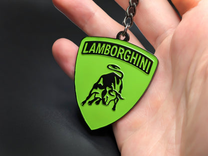 Hand holding a lime green and gunmetal Lamborghini enamel badge keychain to show the premium weight and metallic finish.