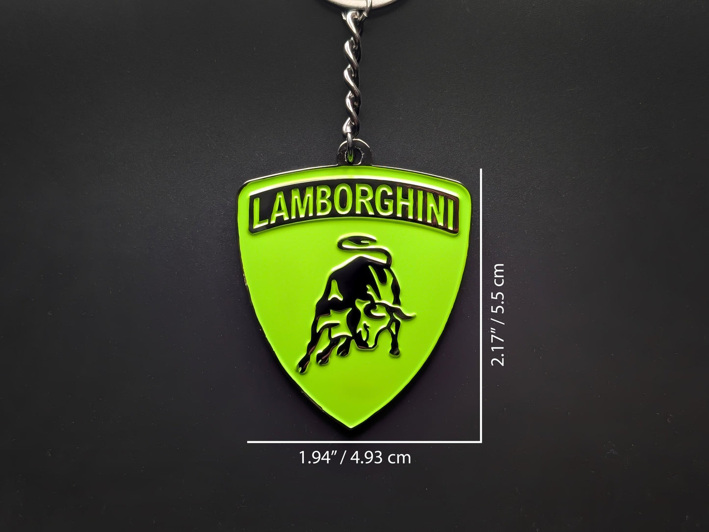 Dimension shot of the Lamborghini green badge keychain showing a size of 2.17 inches by 1.94 inches (5.5 cm by 4.93 cm).