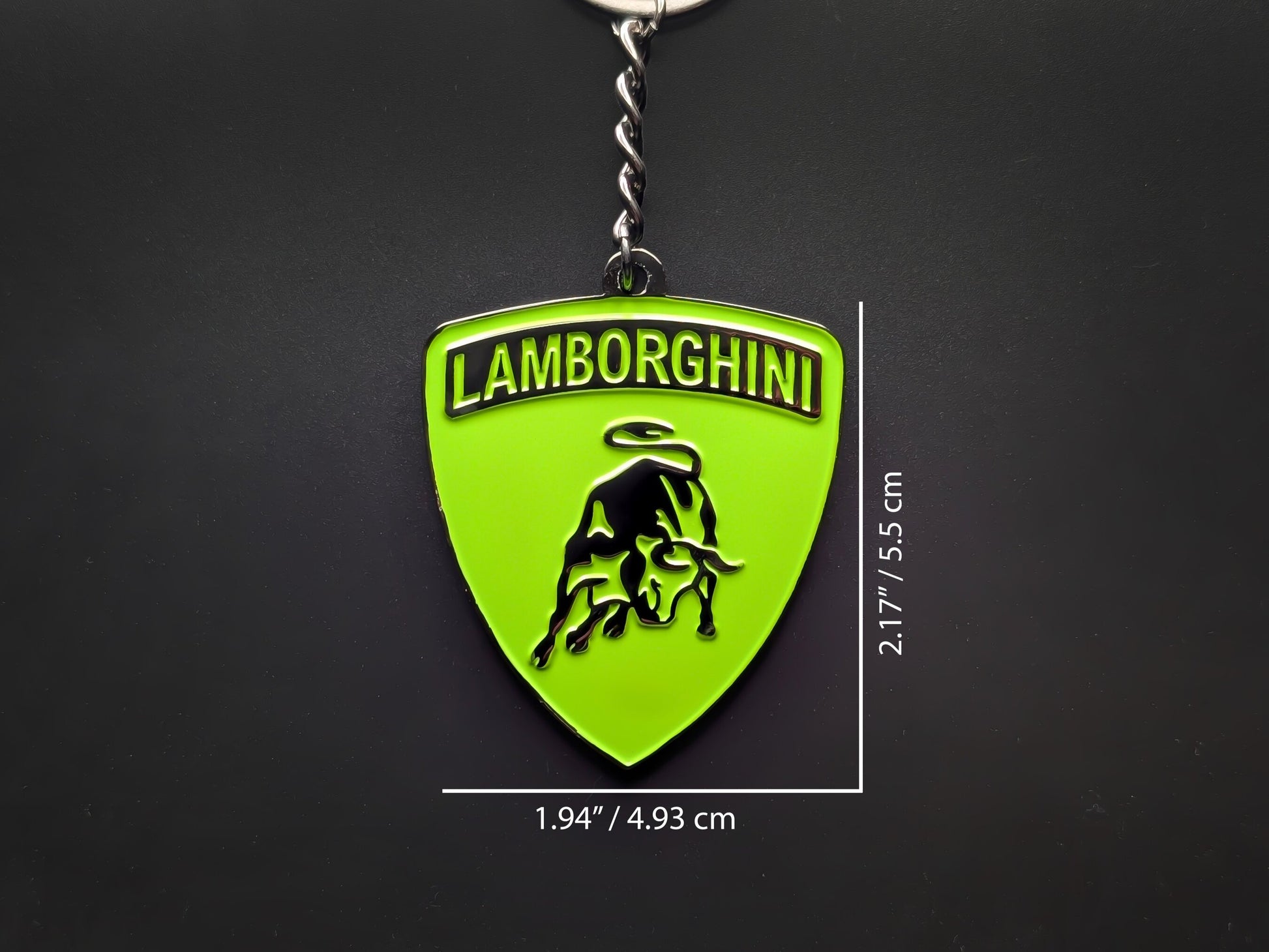 Dimension shot of the Lamborghini green badge keychain showing a size of 2.17 inches by 1.94 inches (5.5 cm by 4.93 cm).